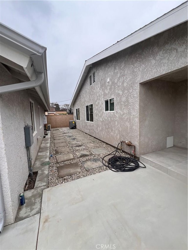 view of home's exterior featuring a patio area, fence, central AC, and stucco siding