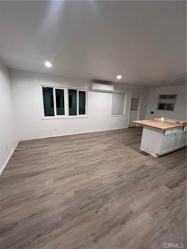 kitchen featuring dark wood finished floors, recessed lighting, wooden counters, an AC wall unit, and open floor plan