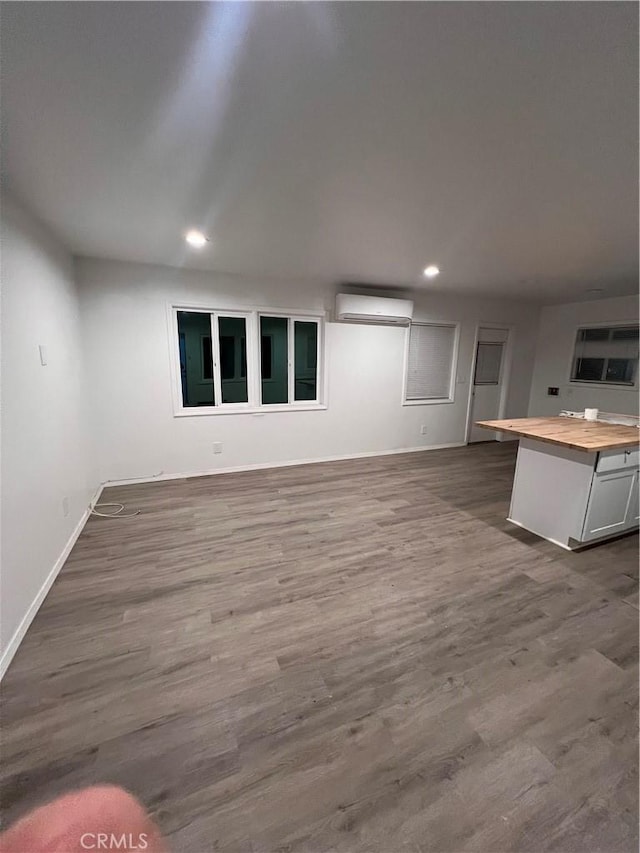 interior space featuring dark wood-type flooring, recessed lighting, a wall mounted air conditioner, and baseboards