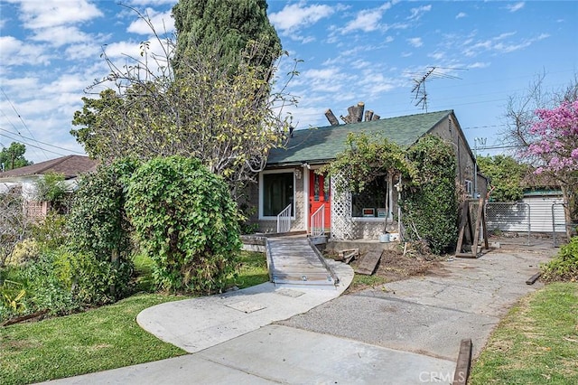 obstructed view of property featuring fence and roof with shingles