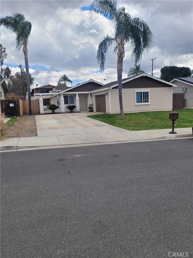 view of front of property with concrete driveway, board and batten siding, fence, a garage, and a front lawn