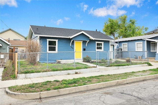 bungalow-style home with roof with shingles, a fenced front yard, and a gate