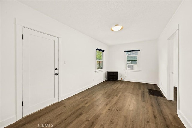 spare room featuring dark wood-style floors and baseboards