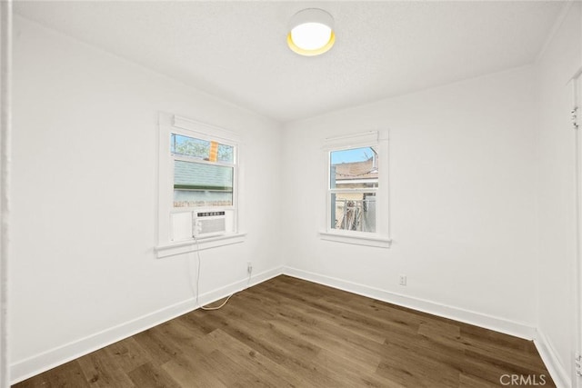 spare room with a healthy amount of sunlight, dark wood finished floors, and baseboards