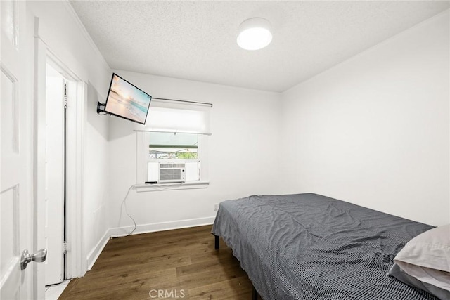 bedroom featuring baseboards, a textured ceiling, cooling unit, and wood finished floors