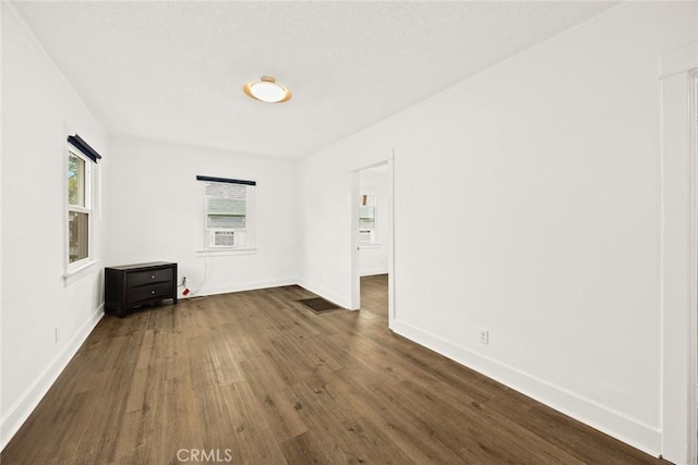 spare room with dark wood finished floors and baseboards