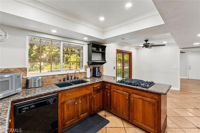 kitchen with dark stone counters, black appliances, a sink, and crown molding