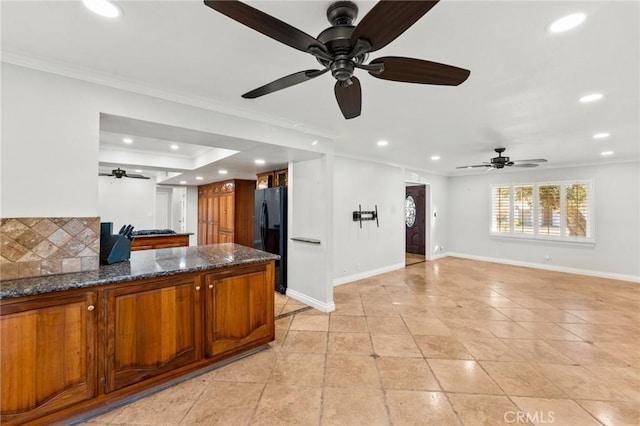 kitchen featuring ornamental molding, brown cabinets, and freestanding refrigerator