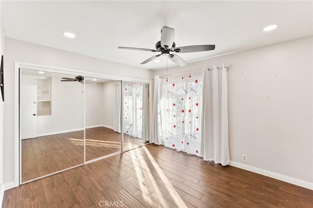 unfurnished bedroom with a closet, baseboards, wood finished floors, and recessed lighting