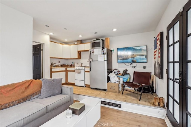 living room with recessed lighting, light wood-style flooring, and french doors