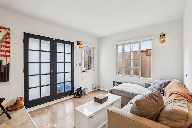 living room featuring light wood-type flooring, baseboards, and french doors