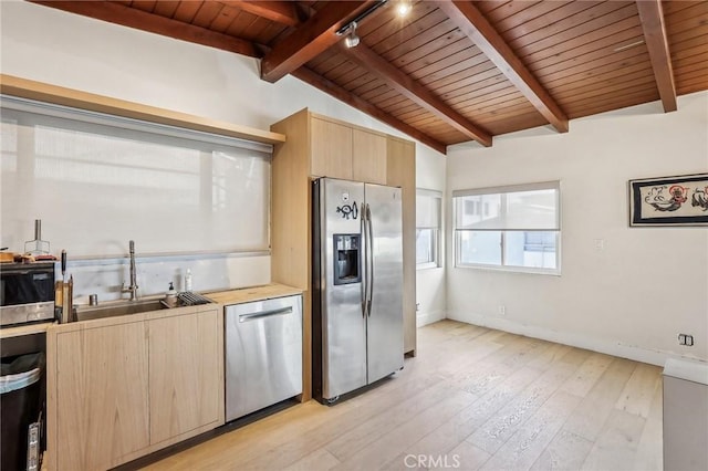 kitchen with lofted ceiling with beams, light brown cabinets, stainless steel appliances, a sink, and light wood-style floors