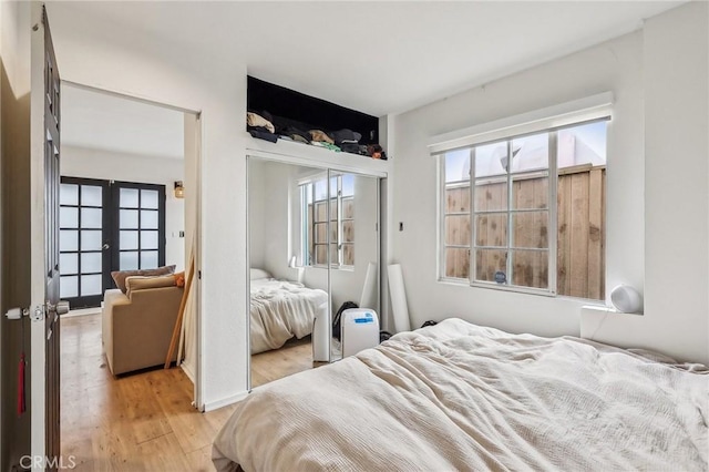 bedroom with french doors, multiple windows, a closet, and light wood-style floors