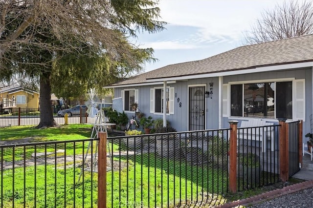 view of front of home featuring roof with shingles, a front yard, and a fenced front yard