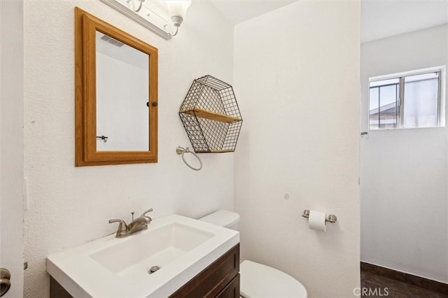 bathroom with toilet, visible vents, and vanity