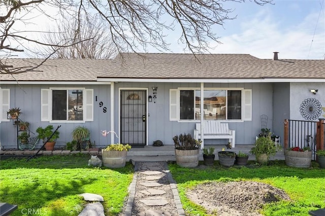 view of front facade featuring a shingled roof, board and batten siding, and a front lawn