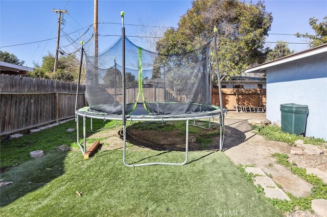 view of yard featuring a trampoline and a fenced backyard