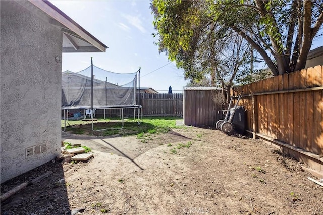 view of yard featuring a trampoline and a fenced backyard