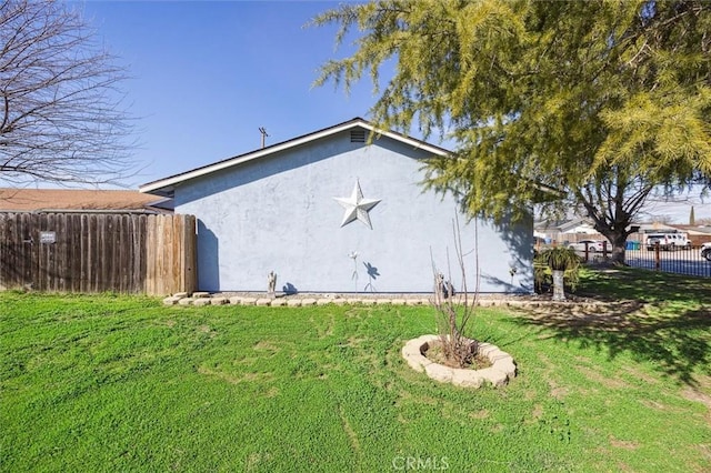 view of home's exterior with a yard, fence, and stucco siding