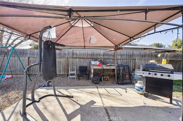 view of patio with a playground, fence, and grilling area