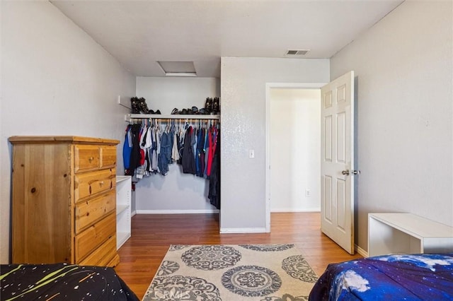 bedroom featuring a closet, visible vents, attic access, wood finished floors, and baseboards