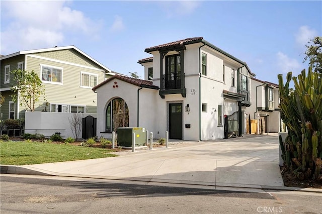 view of front of property featuring concrete driveway, fence, a tiled roof, and stucco siding