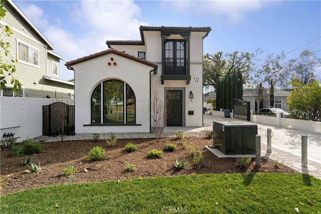 view of front of house featuring a tiled roof, a gate, fence, and stucco siding