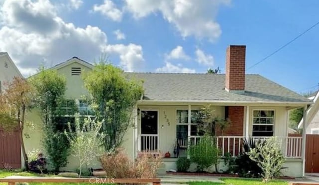 view of front of home with fence, covered porch, and a chimney