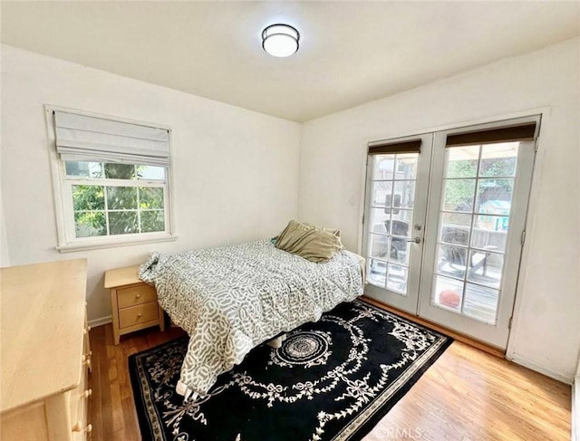 bedroom with french doors, wood finished floors, baseboards, and access to exterior