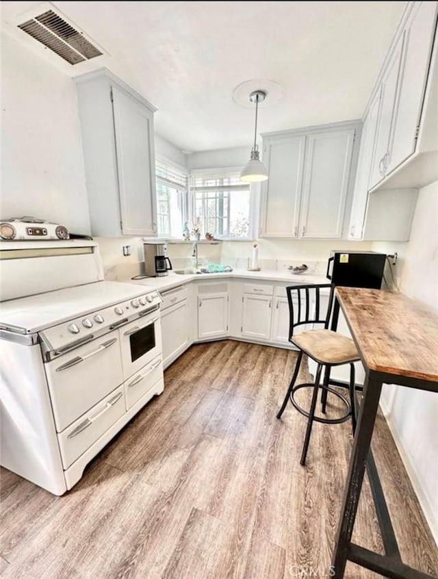 kitchen with double oven range, visible vents, light wood-style flooring, a sink, and light countertops