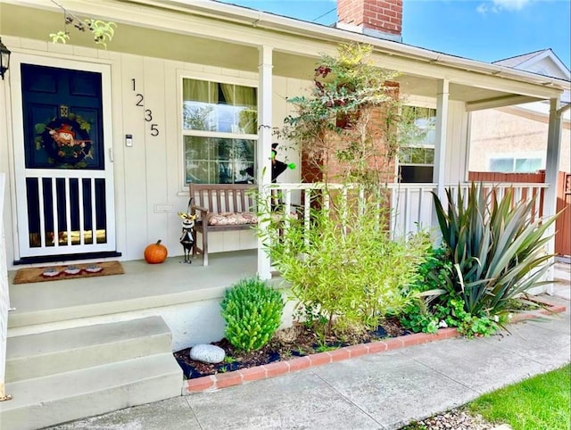 doorway to property featuring a porch and a chimney