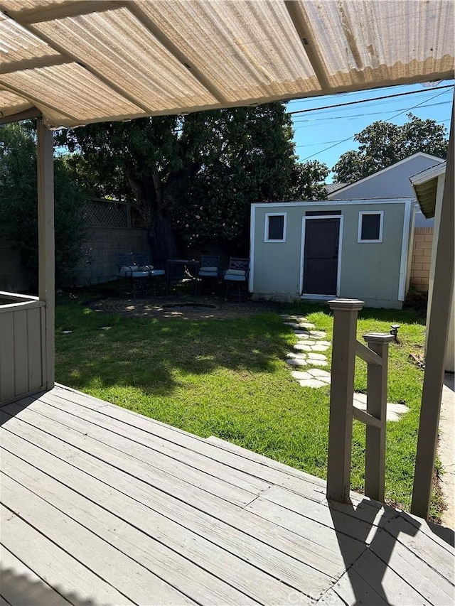 deck featuring a lawn, an outdoor structure, and fence