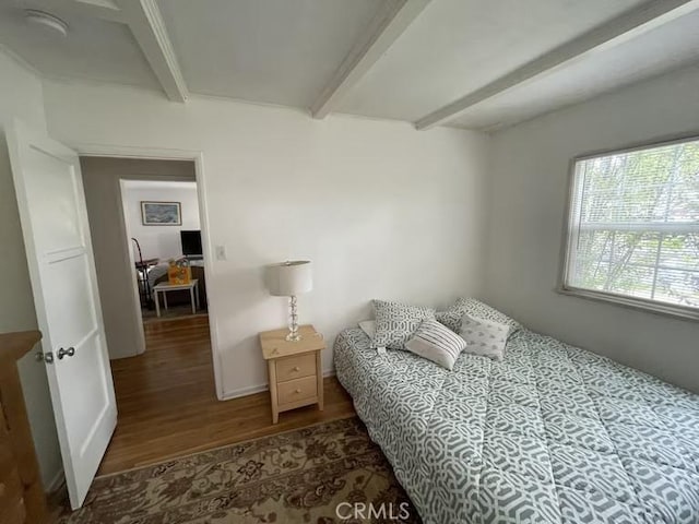 bedroom with beam ceiling and wood finished floors