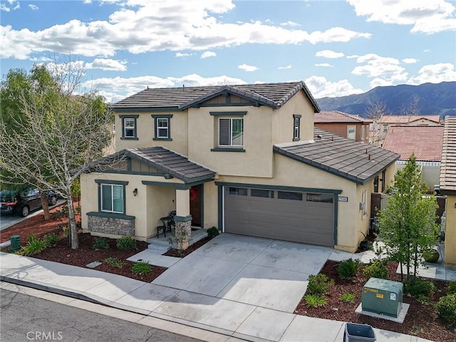 traditional-style home with a tile roof, a mountain view, concrete driveway, and stucco siding