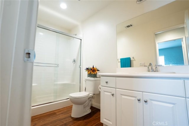 full bath with toilet, wood finished floors, visible vents, vanity, and a shower stall