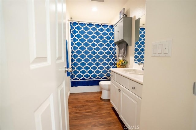 bathroom featuring toilet, a shower with curtain, wood finished floors, and vanity