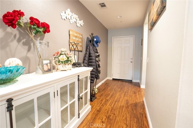 corridor featuring light wood-style flooring, visible vents, and baseboards