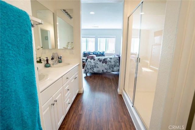 ensuite bathroom with a stall shower, wood finished floors, a sink, and ensuite bathroom