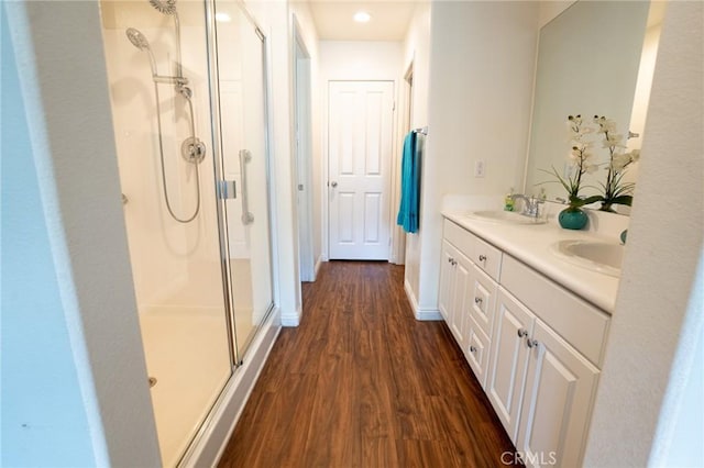 full bath featuring double vanity, wood finished floors, a sink, and a shower stall