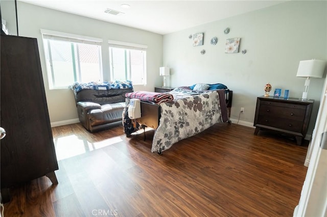 bedroom with wood finished floors, visible vents, and baseboards