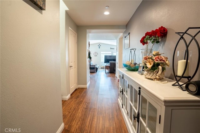 hall with a textured wall, dark wood finished floors, and baseboards