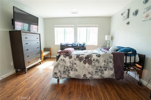 bedroom featuring baseboards, visible vents, and wood finished floors