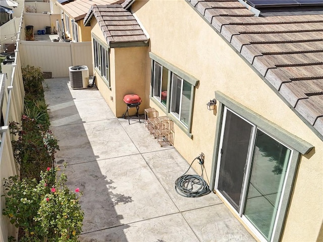 view of property exterior with a patio area, a tile roof, fence, and stucco siding