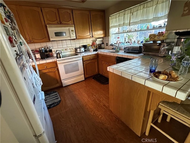 kitchen featuring dark wood-style floors, tile countertops, tasteful backsplash, a sink, and white appliances