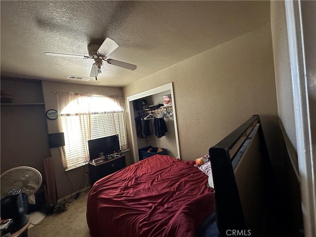 bedroom featuring a closet, visible vents, a textured wall, ceiling fan, and a textured ceiling