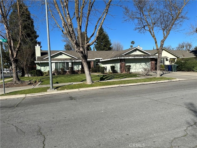 ranch-style home with an attached garage, brick siding, concrete driveway, and a front yard