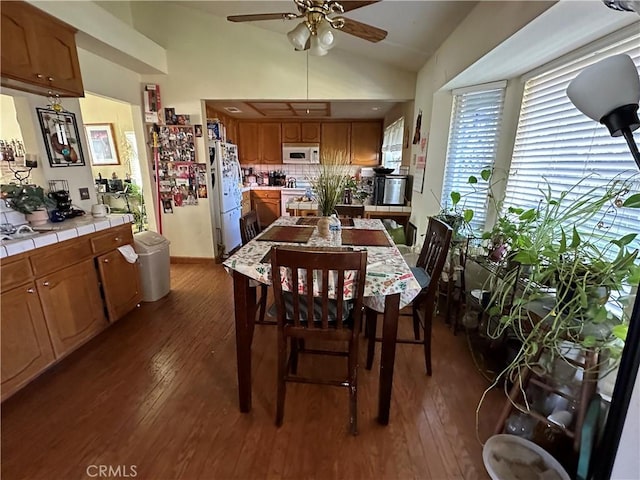 dining area featuring dark wood-type flooring, lofted ceiling, and a ceiling fan