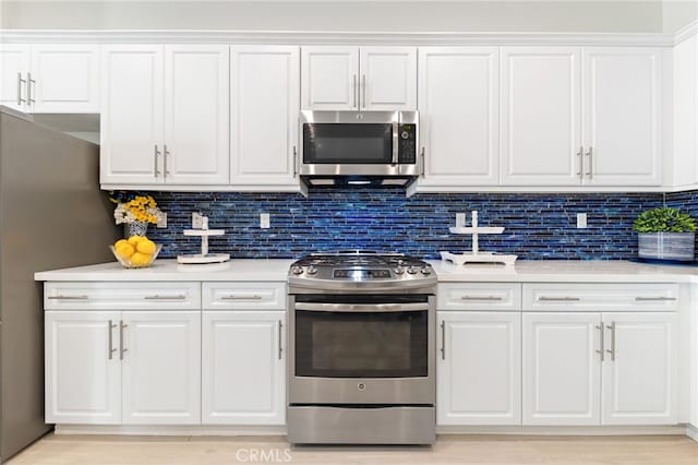 kitchen with light wood finished floors, stainless steel appliances, tasteful backsplash, light countertops, and white cabinets