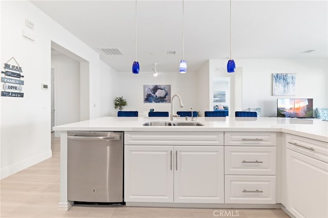 kitchen featuring light countertops, stainless steel dishwasher, a sink, and white cabinetry