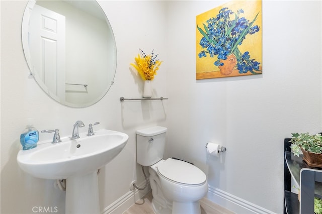 half bath featuring a sink, toilet, and baseboards